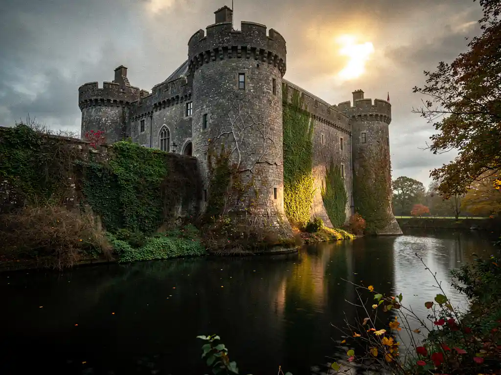Stone castle with water-filled moat, ivy-covered weathered walls bathed in golden light breaking through overcast sky.